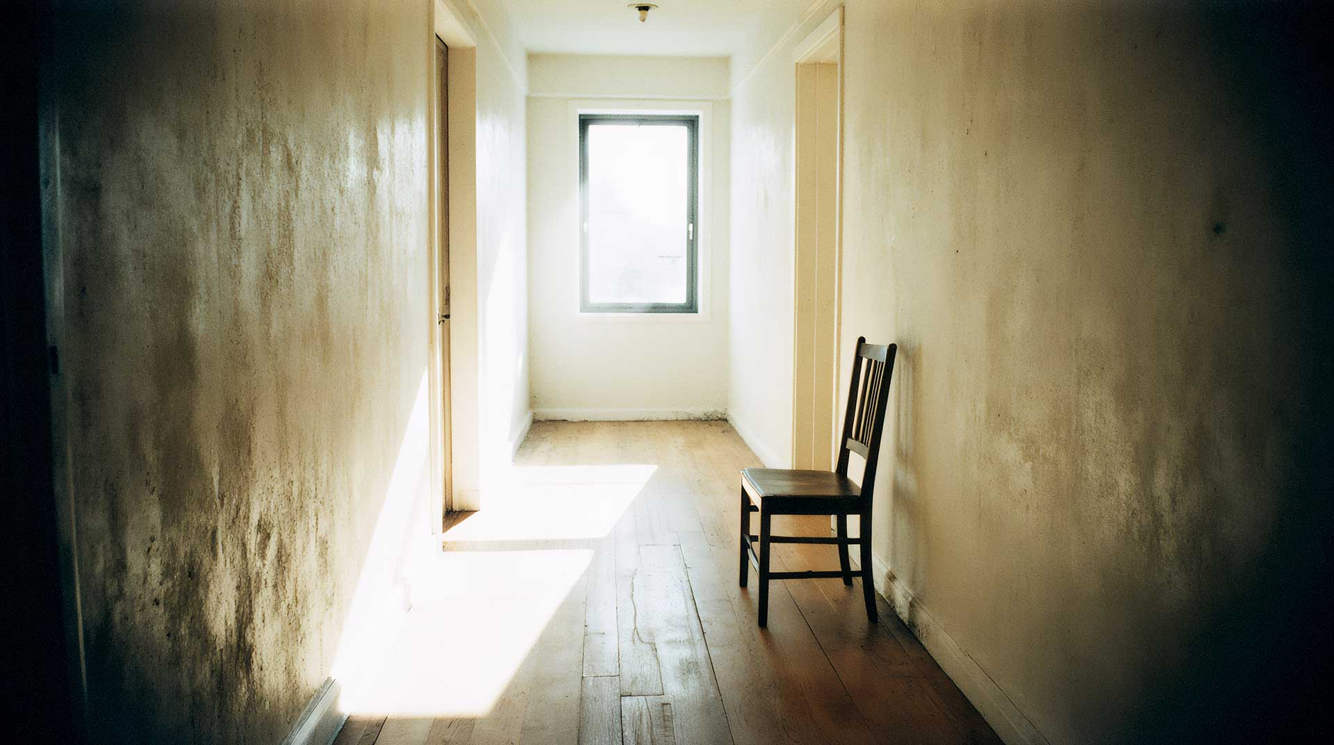 A quiet hallway with soft morning light casting long shadows across the floor